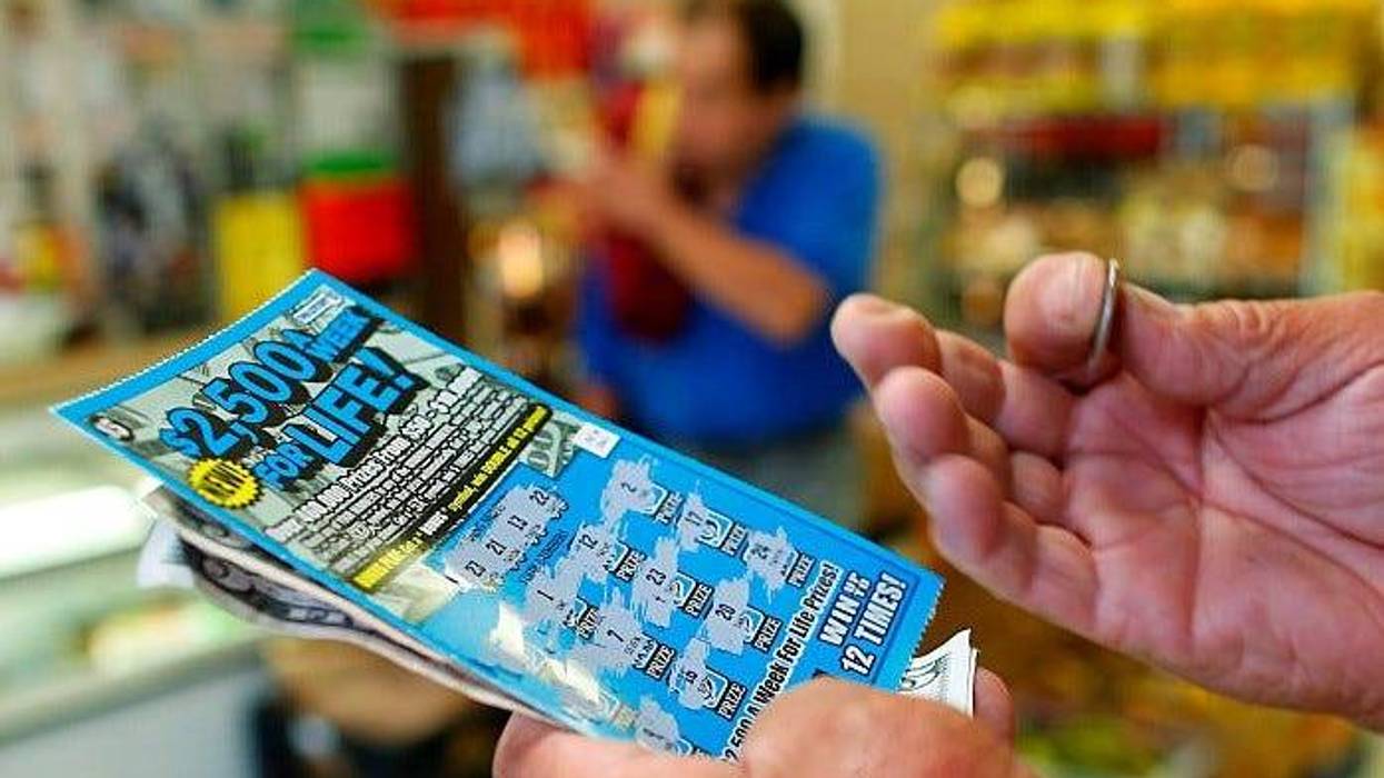 man scratching lottery ticket at store