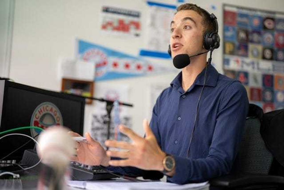 Man sits at a desk with a microphone