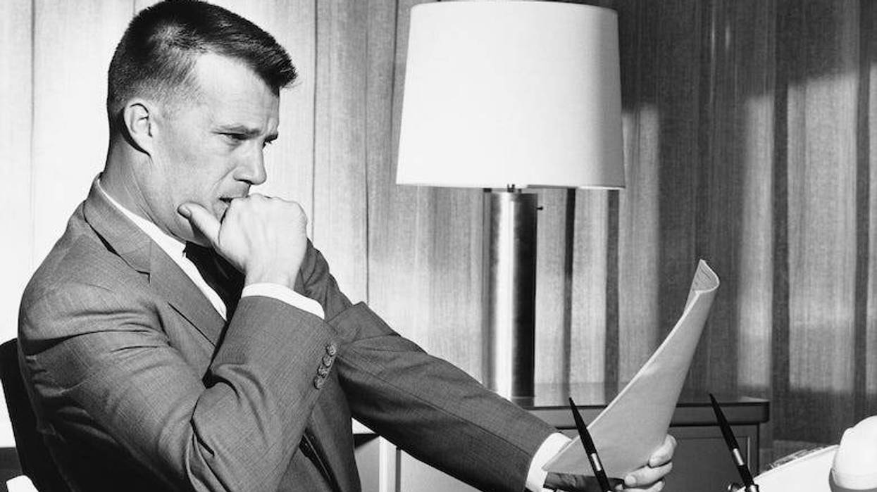 Man sitting at his desk reading a document in the 1950s