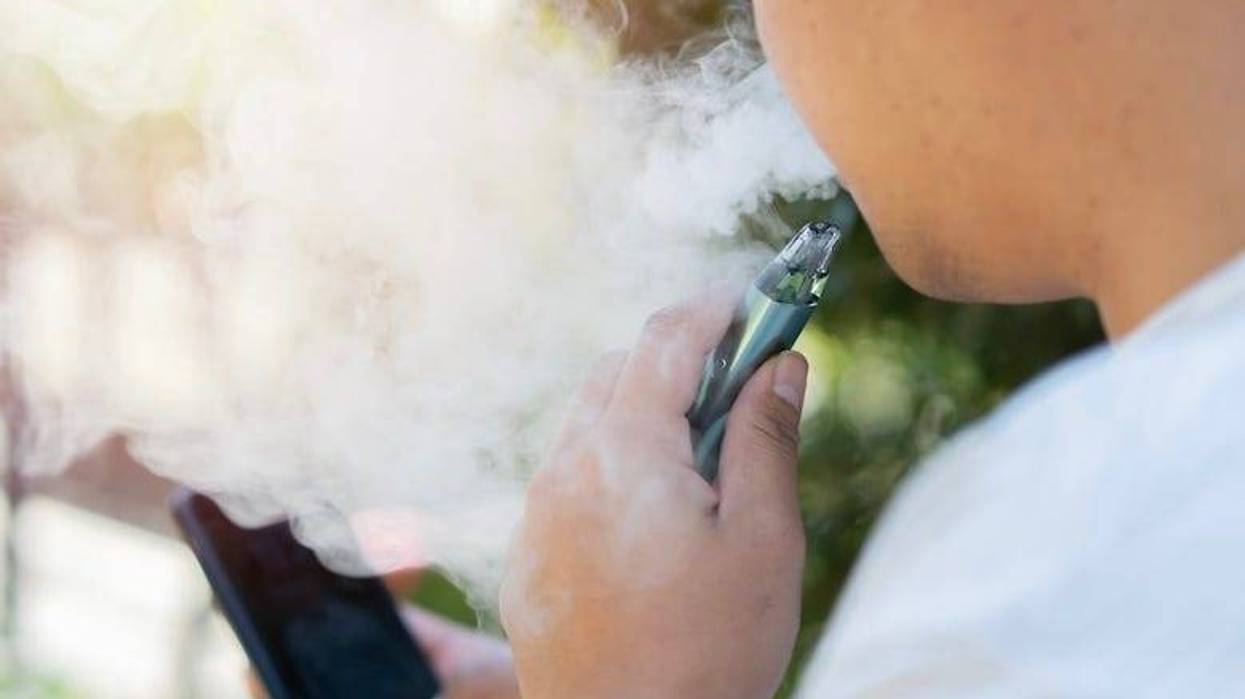 Man smoking an e-cigarette while looking at his phone