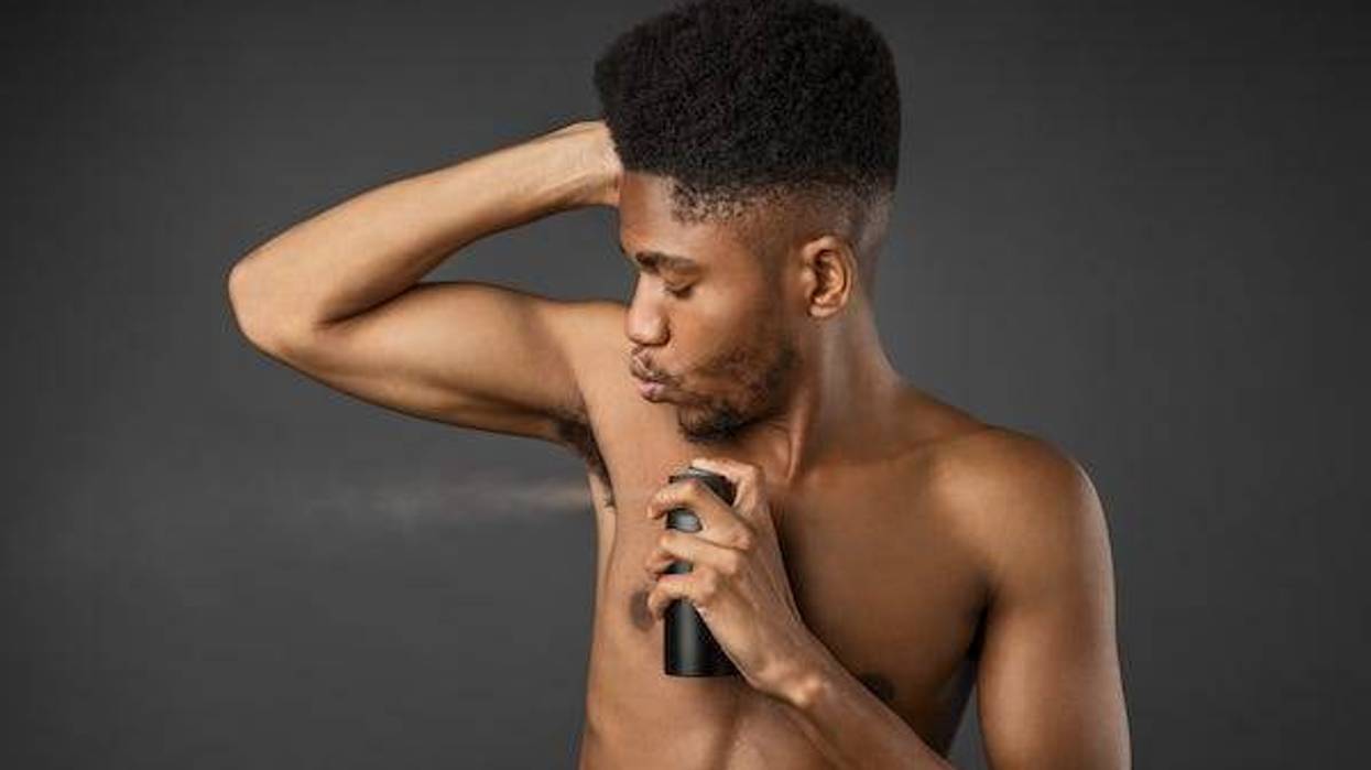 Man spraying body spray under arms