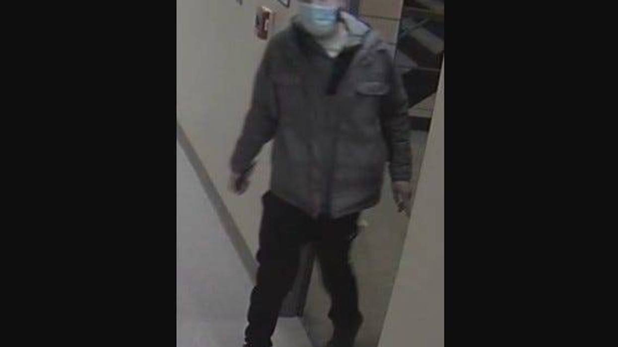 man standing wearing black pants, grey shoes and grey jacket