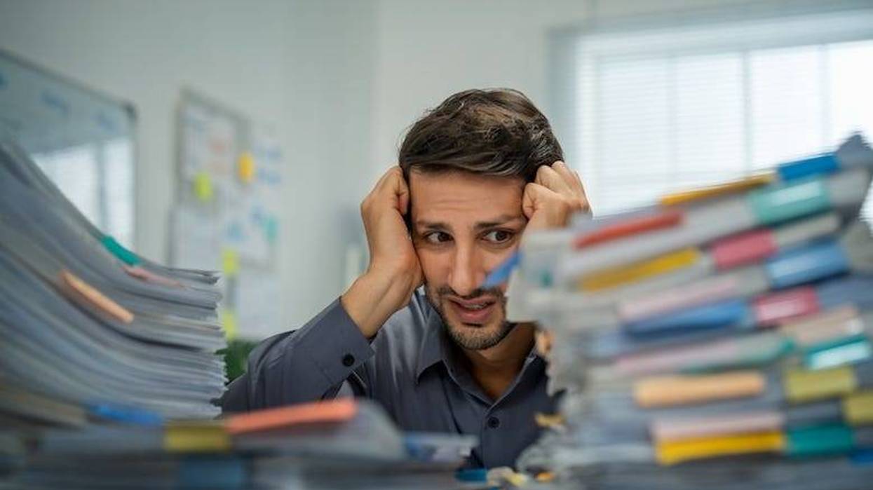 Man staring at piles of papers on his office desk