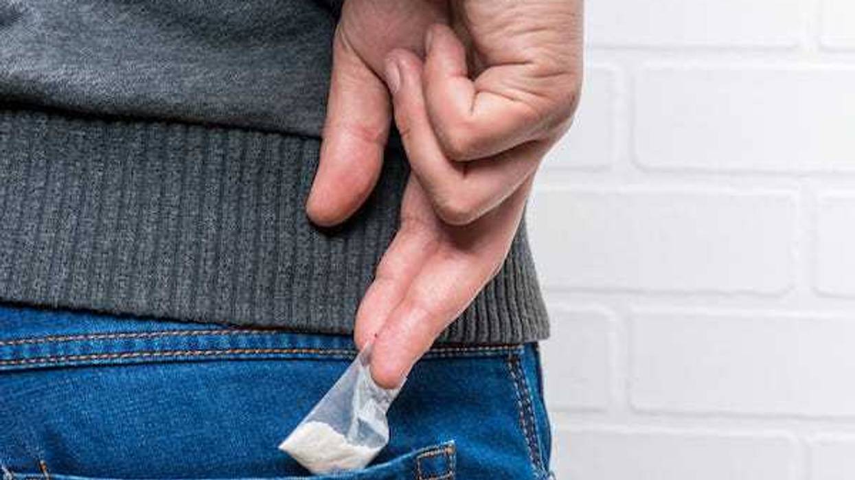 Man taking bag of drugs out of back pocket