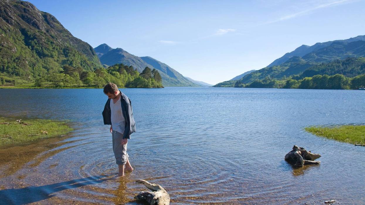 Man walking in rich waters of Loch Shiel, West Highlands