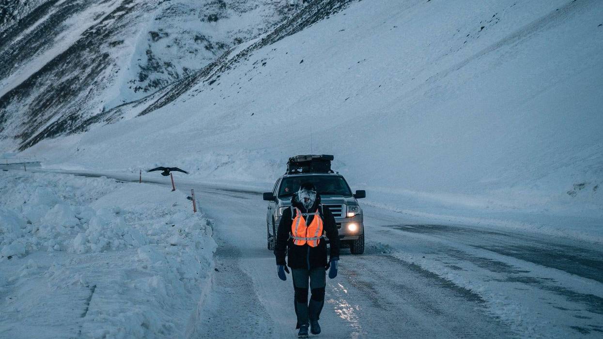 man walking on snow covered mountains in alaska and icy road