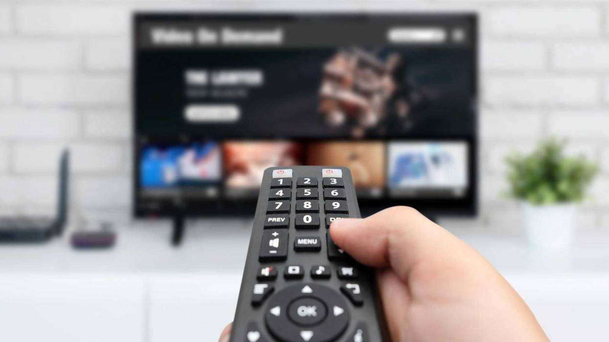 Man watching TV, remote control in hand. VOD service on TV