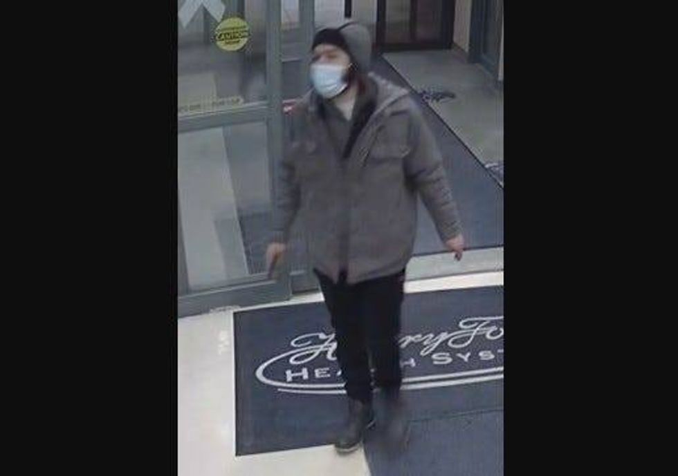 Man wearing black pants, grey coat and hood