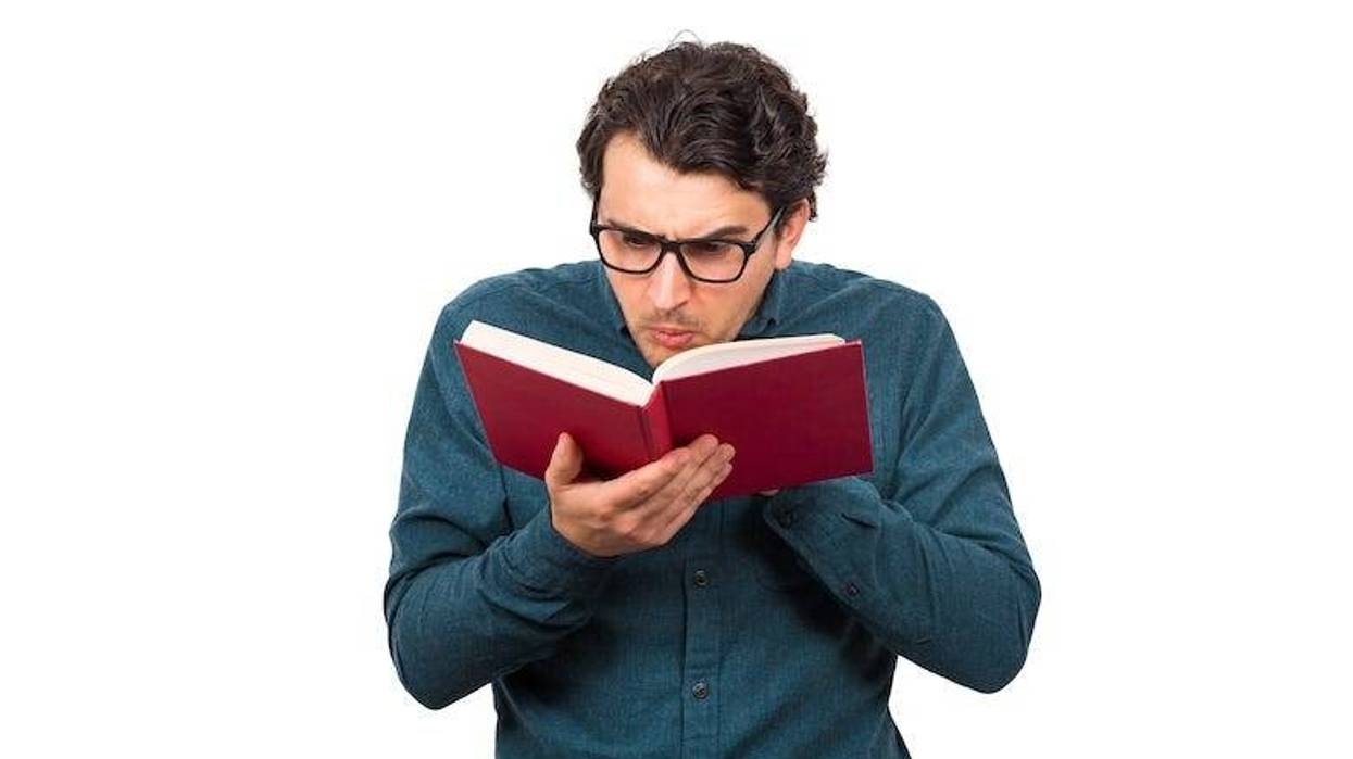 Man wearing glasses confused reading a book