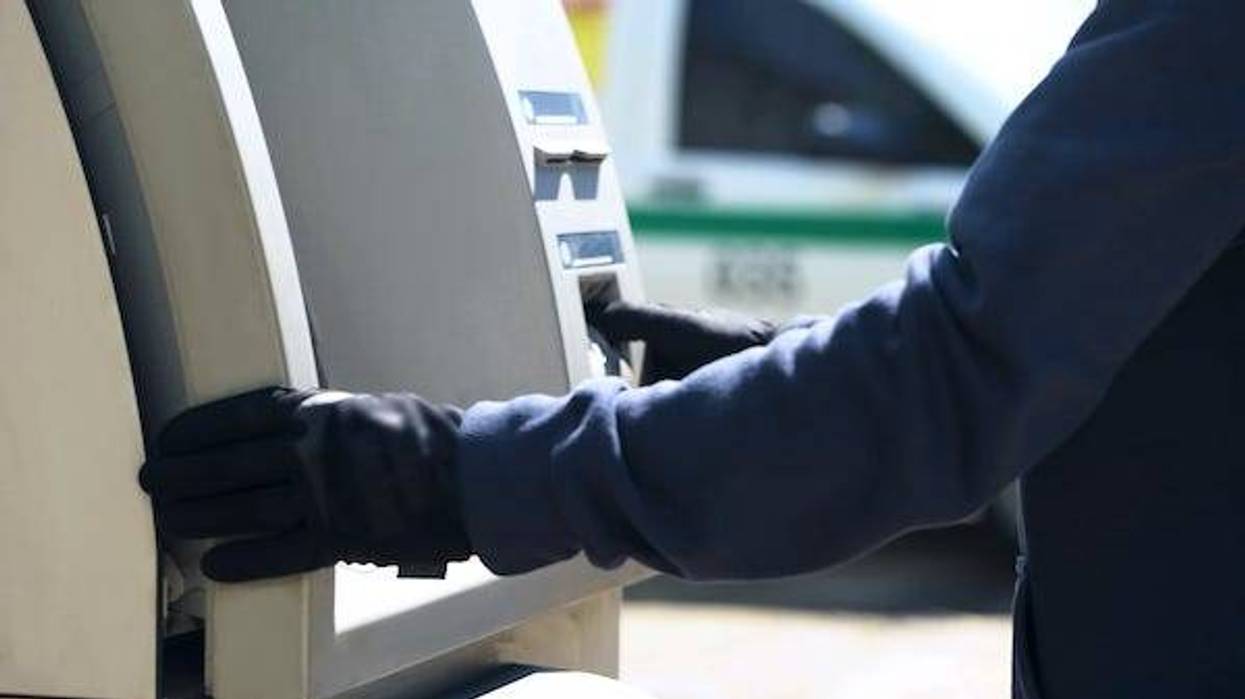 Man wearing gloves handling an ATM