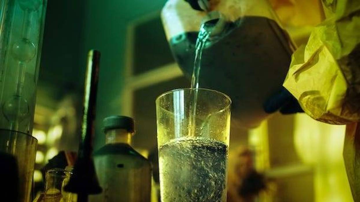 Man wearing protective mask and coveralls pouring liquid in an underground lab