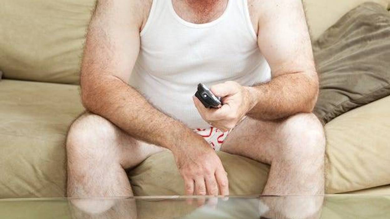 Man wearing underwear sitting on couch watching TV