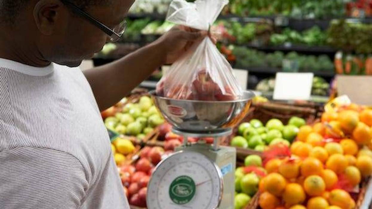 Man weighing plastic bag of apples in a grocery store