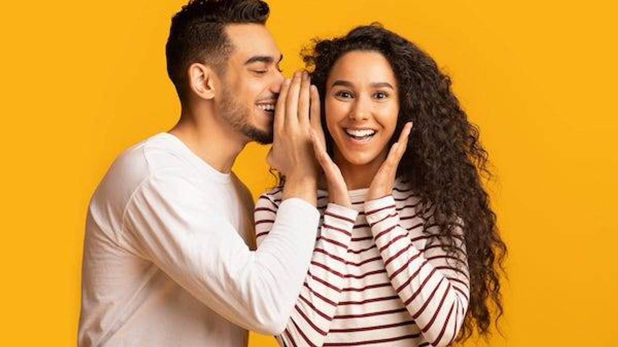 Man whispering into girl's ear