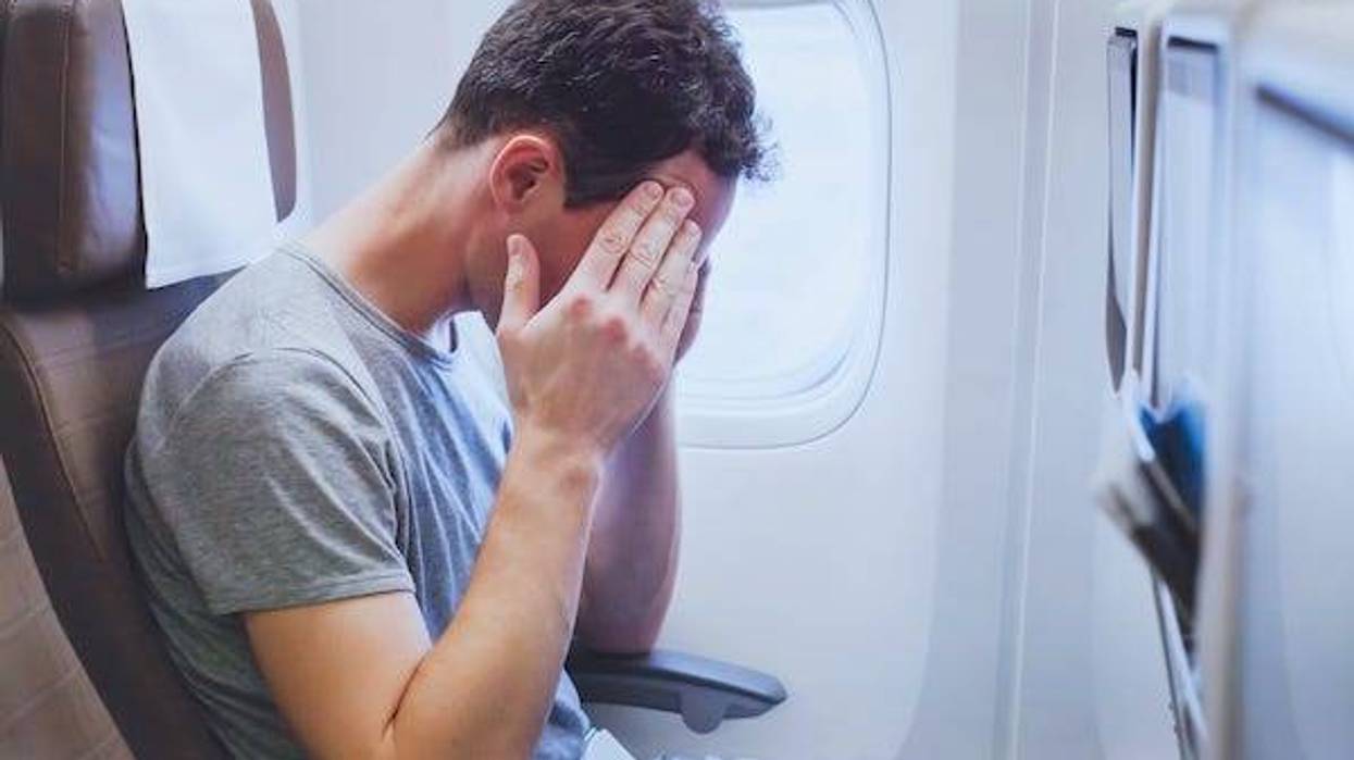 Man with a headache sitting on an airplane