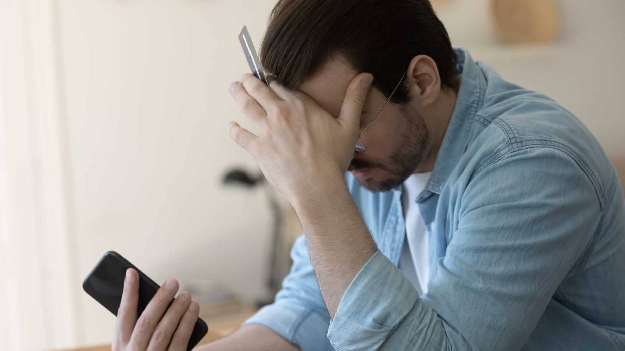 Man with credit card holding head stock image.
