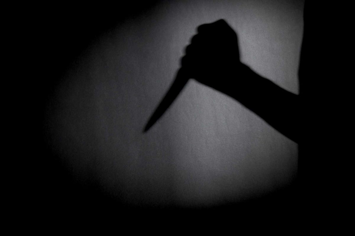 man with knife silhouette over dark wall.