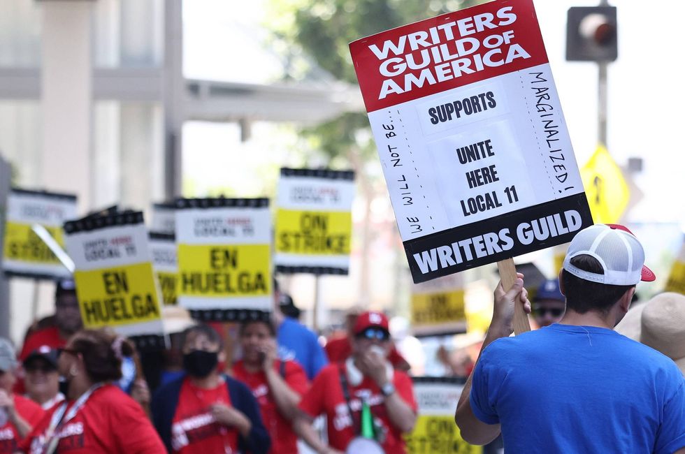 man with sign that says writers guild of america supports unite here local 11