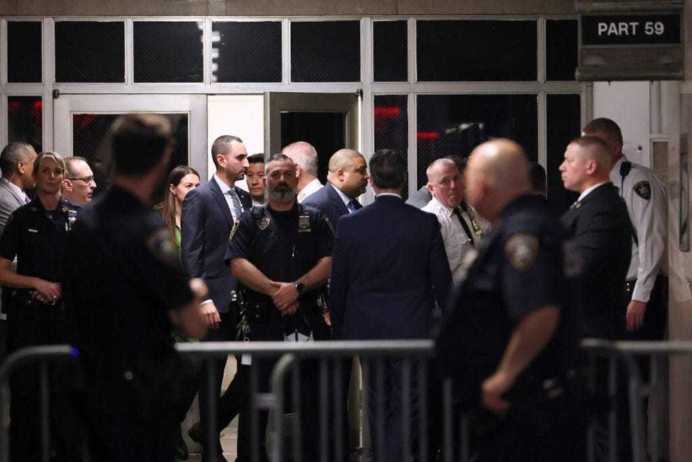 Manhattan District Attorney Alvin Bragg (C) walks through a hallway of the Manhattan Criminal Court during former U.S. President Donald Trump