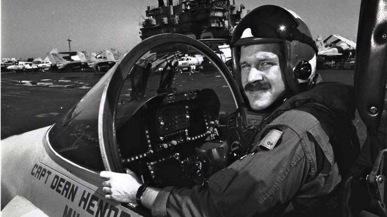 Mark Fox poses in a Hornet with the USS Saratoga in the background a few days after his battle with an Iraqi MiG. Photo courtesy of Fox.