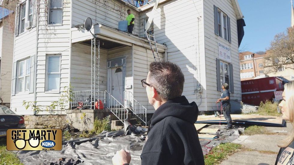 Marty Griffin and Arianna Bazzy look on as crews work to put the new roof on Kenneth