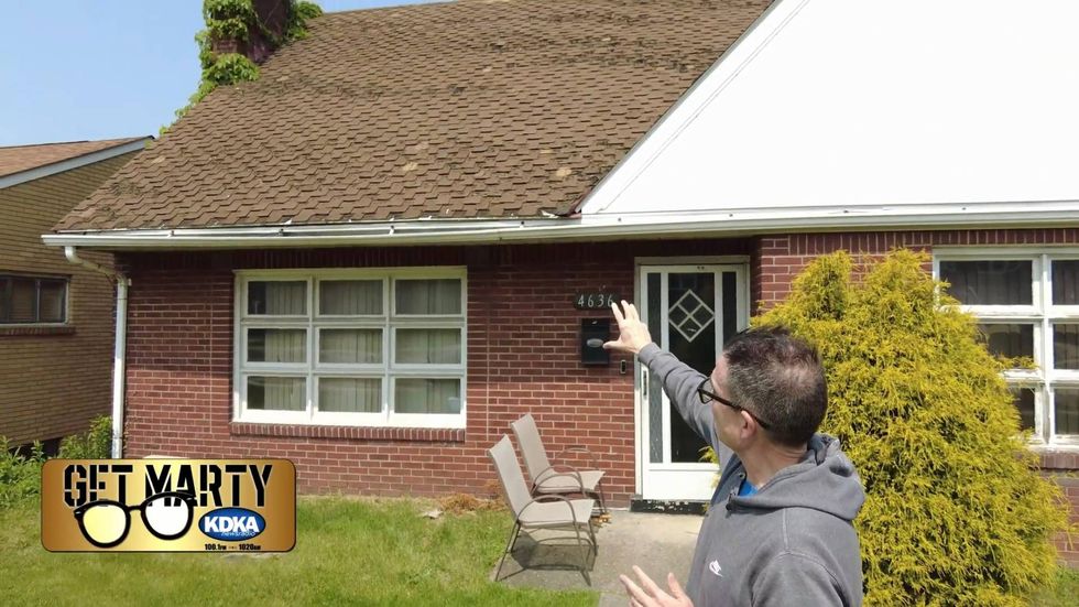 Marty Griffin points to roof and chimney damage outside Suzy