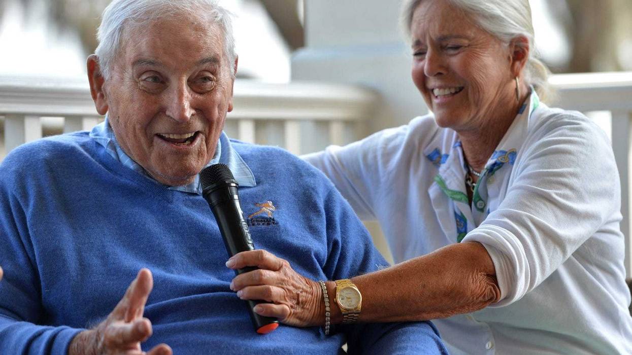 Mary Lujack, right, holds a microphone for her father, Johnny Lujack, winner of the 1947 Heisman Memorial Trophy at The Founder's Club on Tuesday. Lujack spoke to members on the veranda of the clubhouse after accompanying his daughter and some of her friends on the golf course
