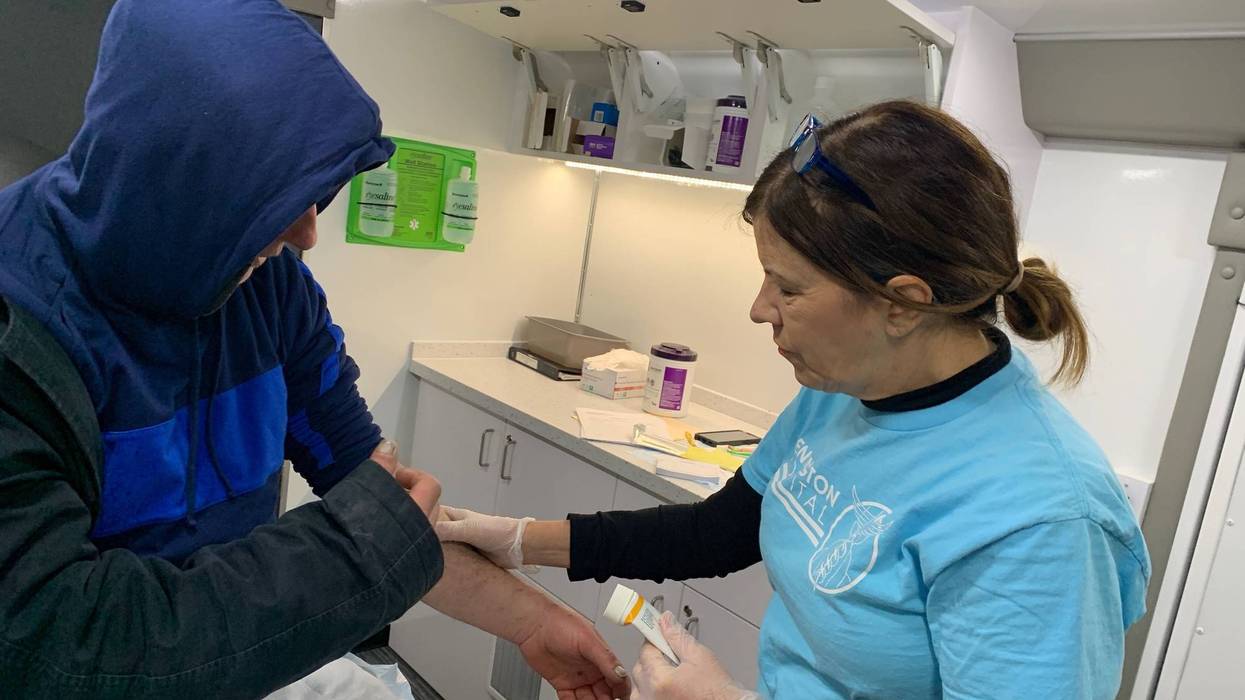 Mary Marquis, a nurse practitioner treating a man inside a van, outfitted by Kensington Hospital, to serve people with wounds from injections of street drugs.