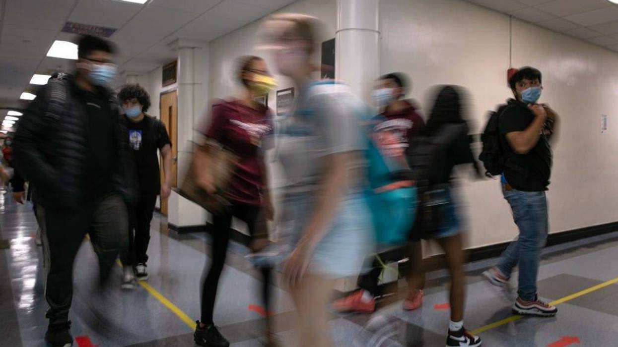 Masked students walk the halls between classes during the first day of school