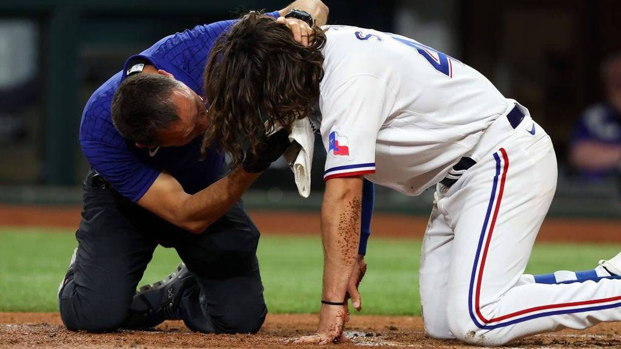 Matt Lucero, athletic trainer for the Texas Rangers, attends to Josh Smith #47 after he was hit in the face by a pitch in the third inning against the Baltimore Orioles at Globe Life Field on April 03, 2023 in Arlington, Texas.