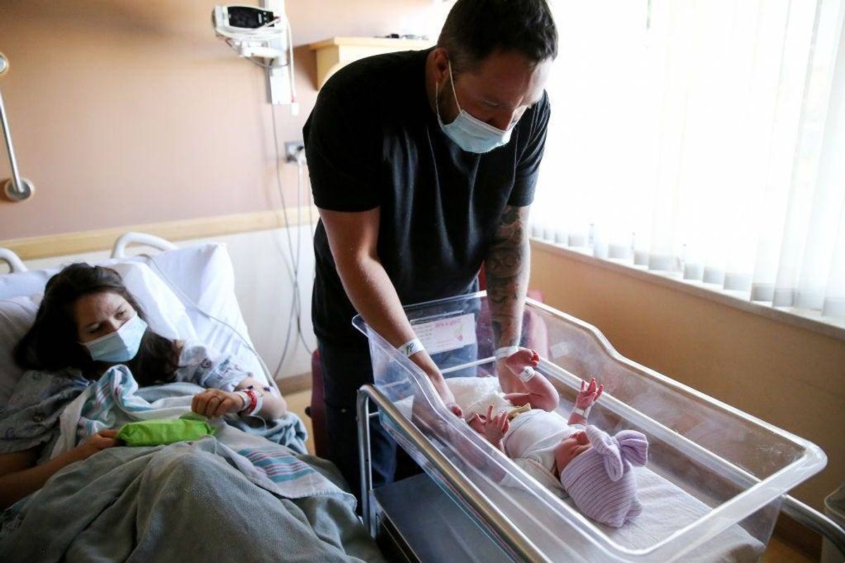 Matthew Carnes prepares to change diapers for his newborn daughter Evelina Carnes as his wife Breanna Llamas keeps watch in the postpartum unit at Providence St. Mary Medical Center on March 30, 2021 in Apple Valley, California.