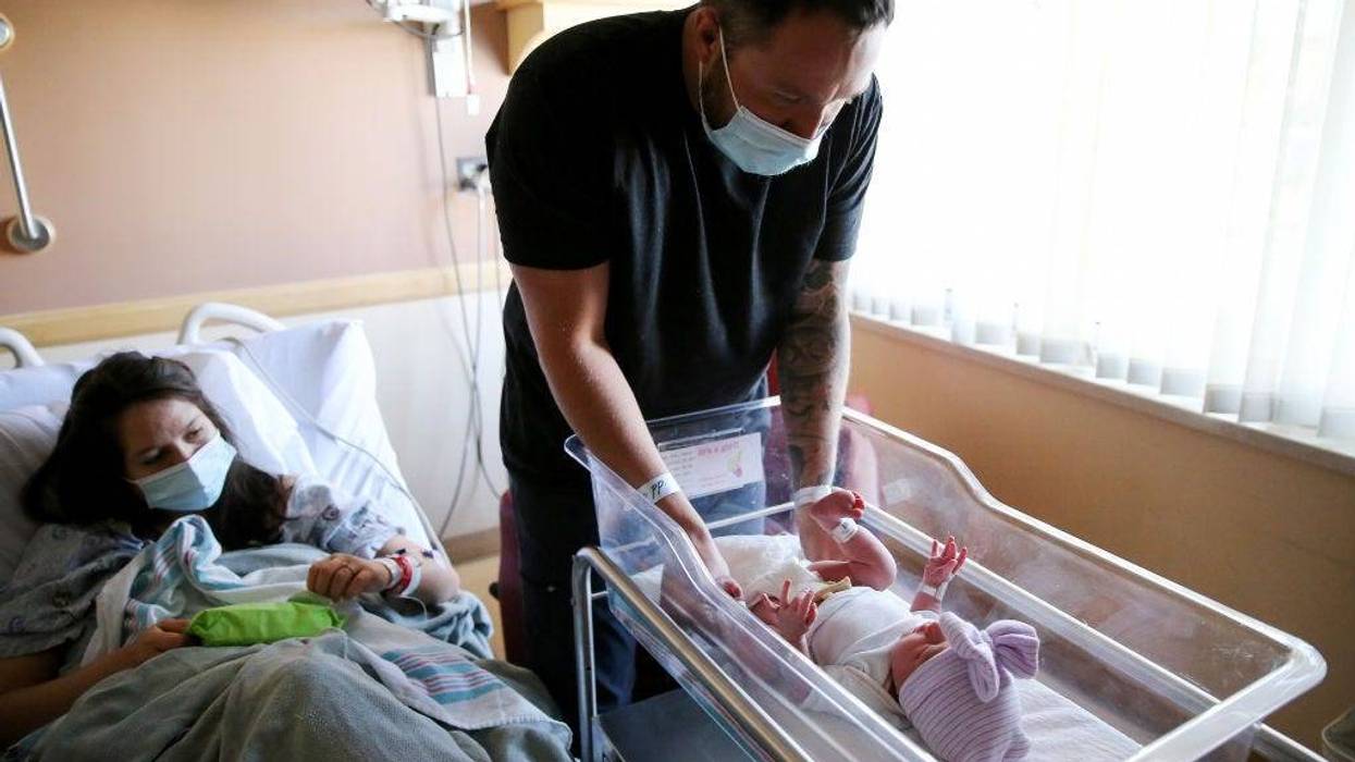 Matthew Carnes prepares to change diapers for his newborn daughter Evelina Carnes as his wife Breanna Llamas keeps watch in the postpartum unit at Providence St. Mary Medical Center on March 30, 2021 in Apple Valley, California.