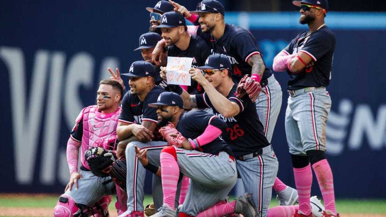 Max Kepler #26 of the Minnesota Twins holds up a '<3 Mom' sign as the team takes a celebratory team photo after their MLB game win against the Toronto Blue Jays at Rogers Centre on May 12, 2024 in Toronto, Canada.