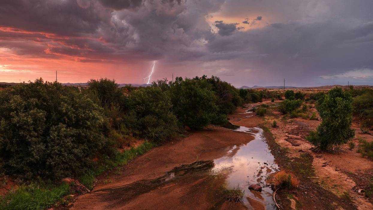 MAYER, ARIZONA - JULY 21: Lightning strikes during a monsoon storm with a nearly dry creek bed in the foreground on July 21, 2022 near Mayer, Arizona. The National Weather Service issued an excessive heat warning for eight counties in Arizona today including Yavapai county. Climate change is making heat waves more frequent and hotter with large swathes of the U.S. currently under excessive heat warnings. Six cities in Arizona, including Phoenix, have declared water shortages amid a climate change-fueled megadrought in the Southwestern United States.