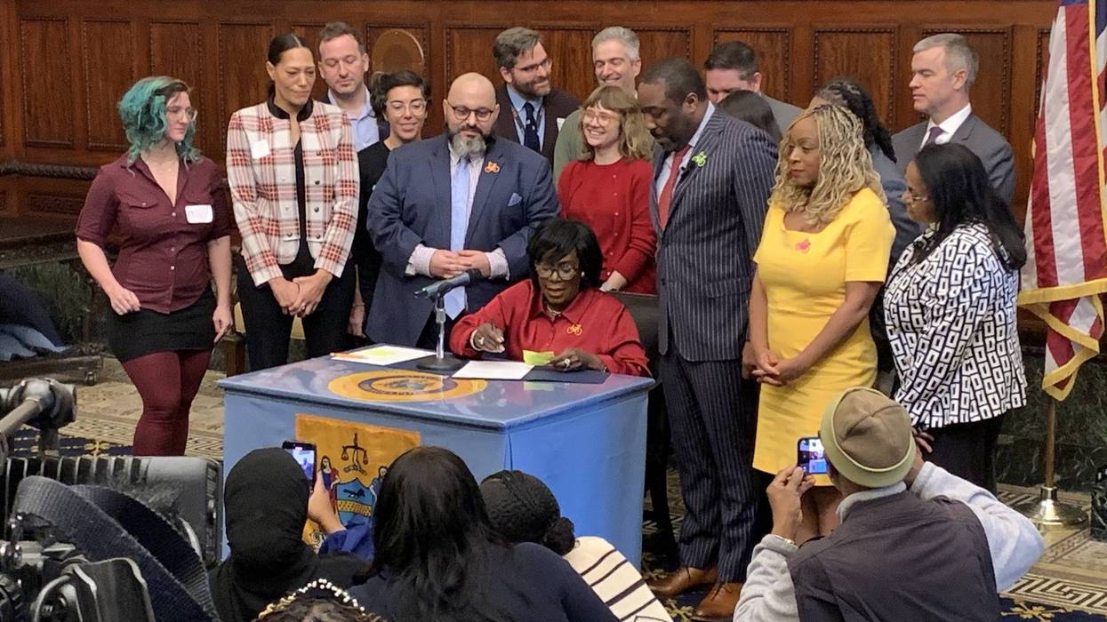 Mayor Cherelle Parker (seated at desk) signs a bill at City Hall on Wednesday increasing fines for drivers who stop in bike lanes.