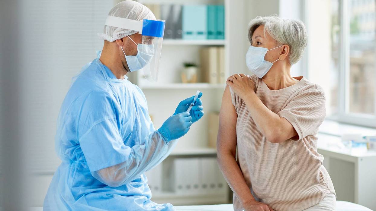 medical professional gives injection to elderly patient