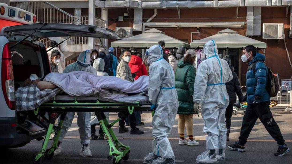 Medical workers wear PPE as they arrive with a patient on a stretcher at a fever clinic on December 9, 2022 in Beijing, China. In a major shift in the country's zero COVID policy, China's government announced Wednesday that people with COVID-19 who have mild or no symptoms will be permitted to quarantine at home instead of at a government facility, are permitted to buy over the counter medications, and will have testing requirements reduced. As part of a 10 point directive, local officials can also no longer lock down entire neighborhoods or cities. (Photo by Kevin Frayer/Getty Images)