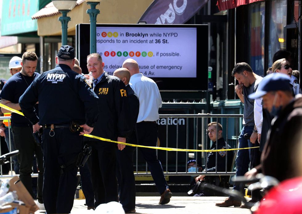 Members of the NYPD work at the scene of a subway shooting in Brooklyn, New York April 12, 2022 where at least ten people were shot during the morning rush hour.