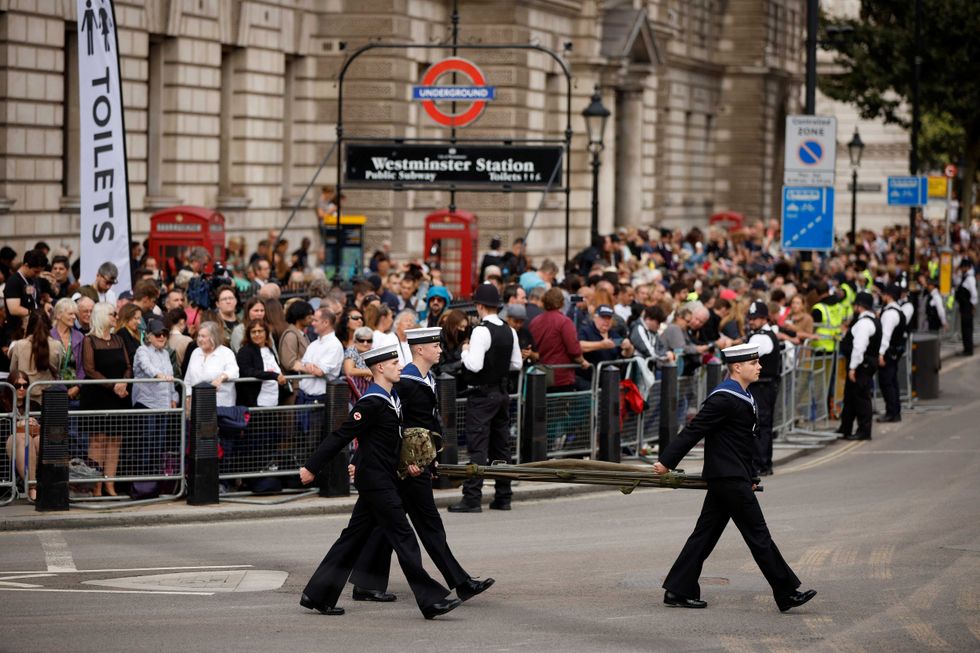 Members of the public wait to see the coffin of Queen Elizabeth II as it is transported from Buckingham Palace to the Palace of Westminster on September 14, 2022 in London