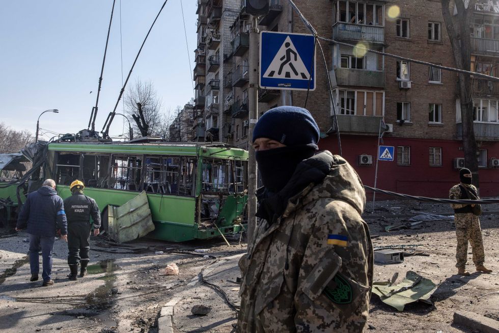 Members of the Ukrainian military stand amid debris from a damaged residential apartment block caused after a Russian rocket was shot down by Ukrainian air defenses on March 14, 2022 in Kyiv, Ukraine