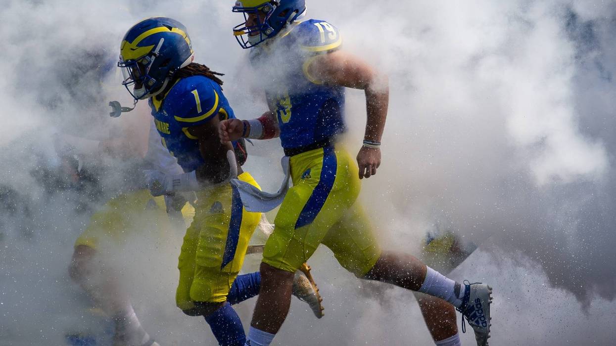 Members of the University of Delaware Blue Hens running onto the football field.