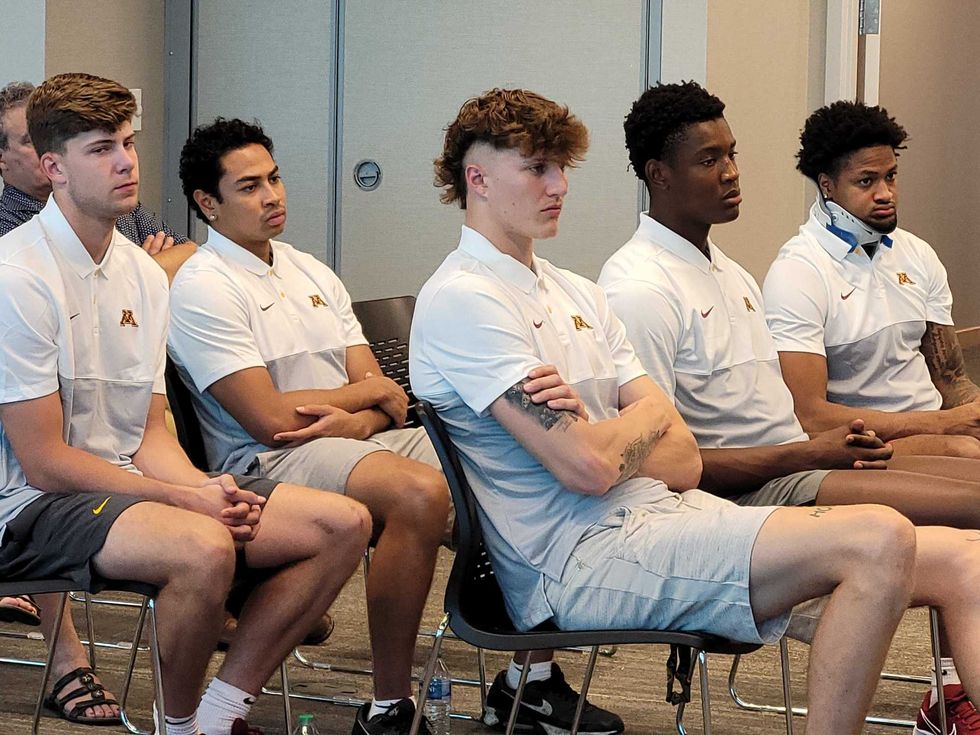 members of UMN Men Basketball team listening in