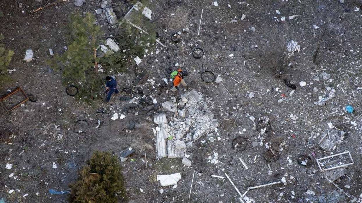 Men search through debris on the ground outside an apartment block that was hit by the debris of an intercepted Russian rocket in the early hours of the morning on March 17, 2022 in Kyiv, Ukraine.