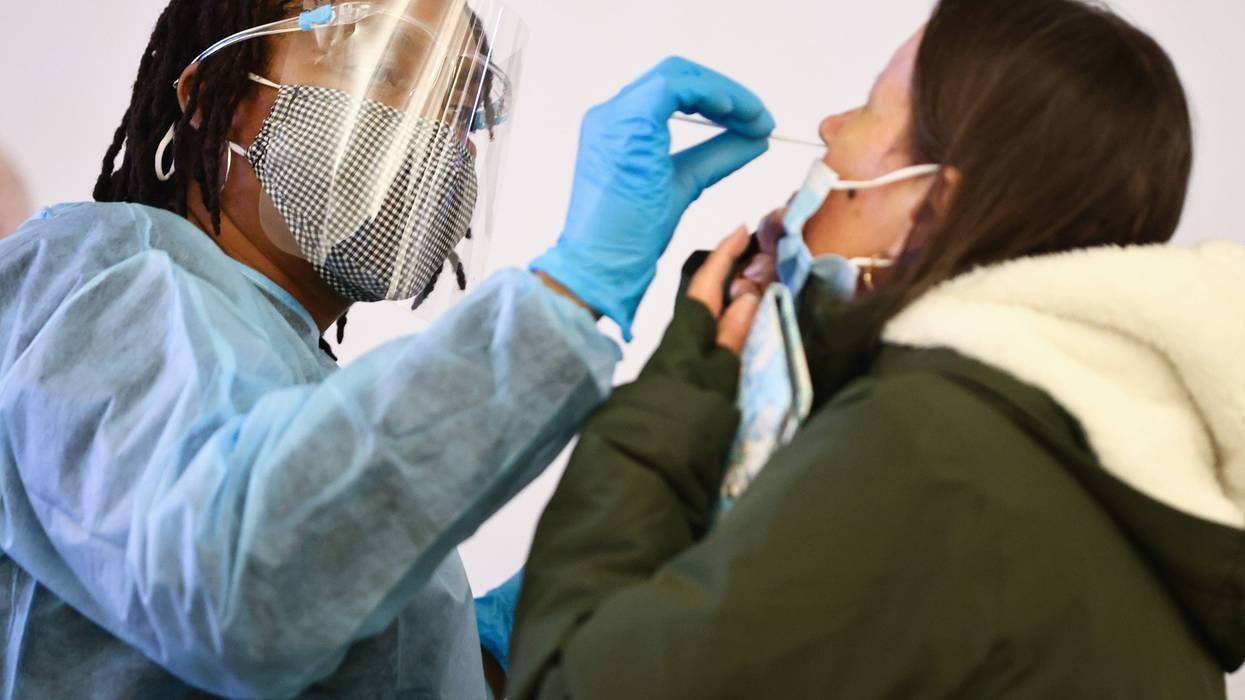 Merline Jimenez (L) administers a COVID-19 nasopharyngeal swab to a person at a testing site located in the international terminal at Los Angeles International Airport (LAX) amid a surge in omicron variant cases on December 21, 2021 in Los Angeles, California.