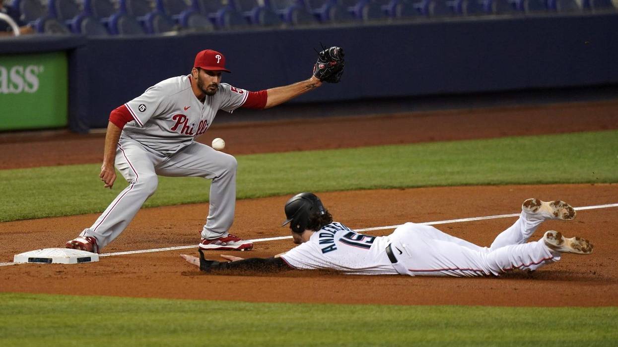 Miami Marlins third baseman Brian Anderson (15) dives safely into third base as Philadelphia Phillies starting pitcher Zach Eflin (56) covers in the second inning at LoanDepot Park.