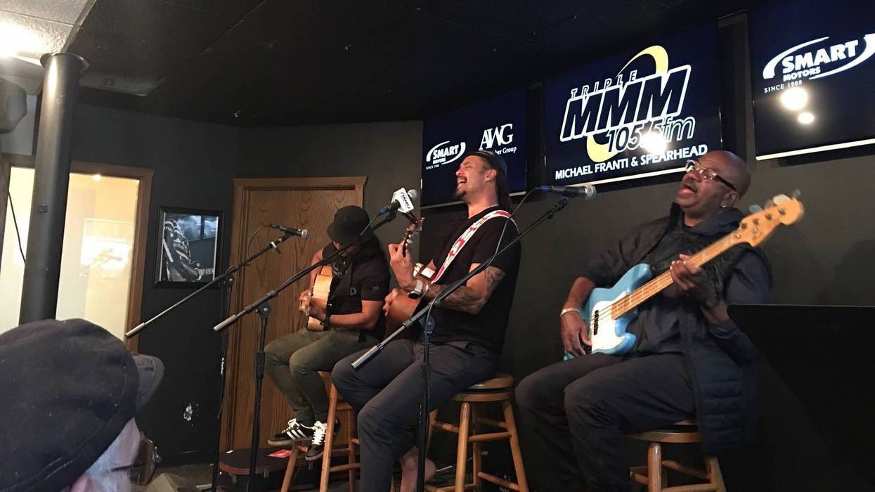 Michael Franti with two band members playing guitars