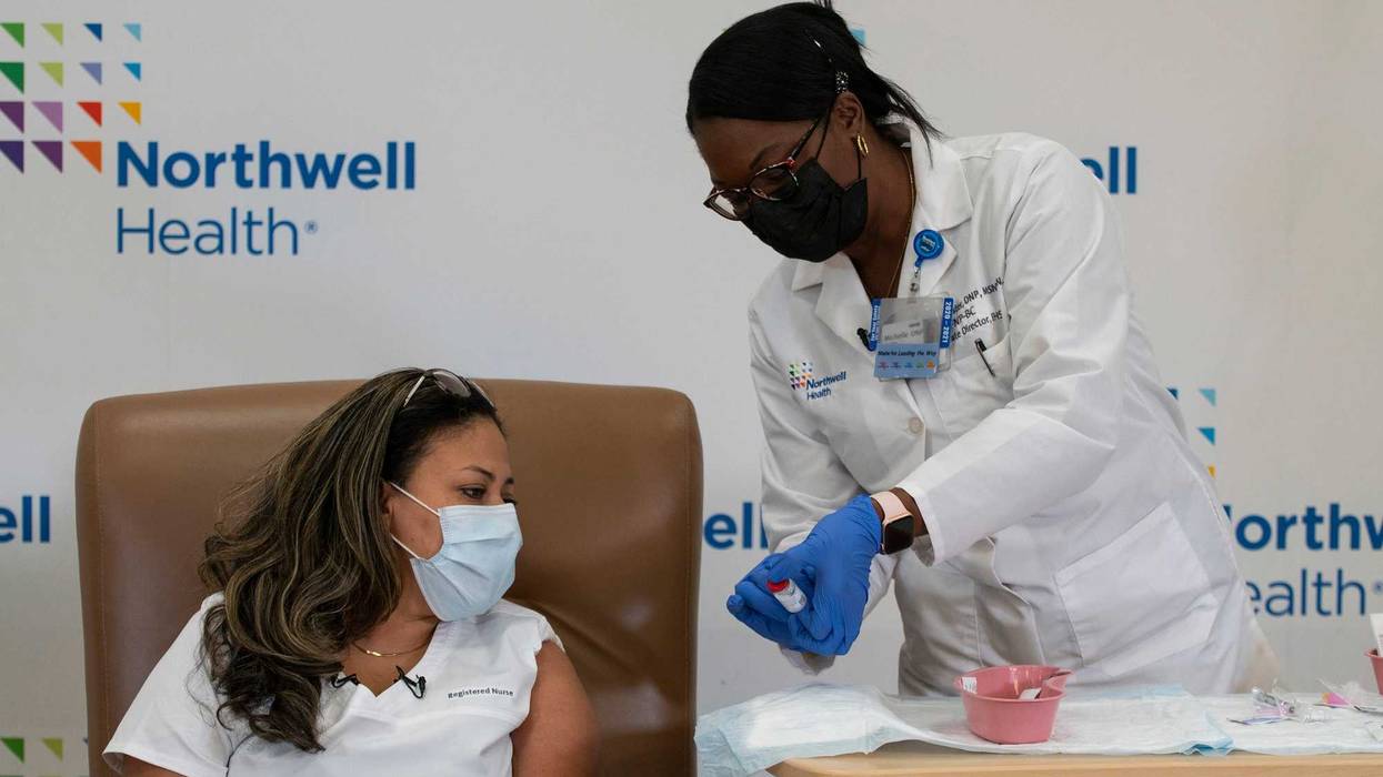 Michelle Chester (R), DNP, director, employee health services, Northwell shows the Moderna coronavirus disease (COVID-19) vaccine to Arlene Ramirez, RN, director, patient care, ED, Long Island Jewish Valley Stream, at Northwell Health's Long Island Jewish Valley Stream hospital in New York City, December 21, 2020.