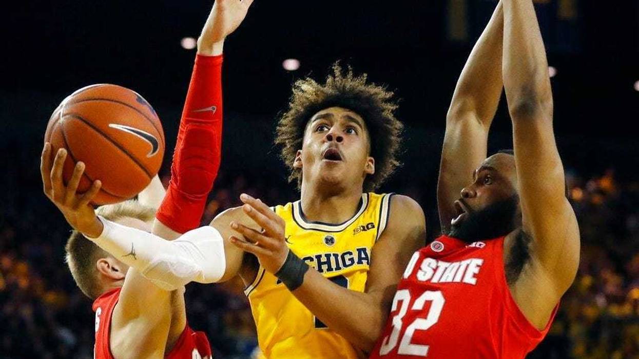 Michigan guard Jordan Poole (2) scores between Ohio State forward Justin Ahrens, left, and guard Keyshawn Woods during the second half of an NCAA college basketball game Tuesday, Jan. 29, 2019, in Ann Arbor, Mich. (AP Photo/Carlos Osorio)