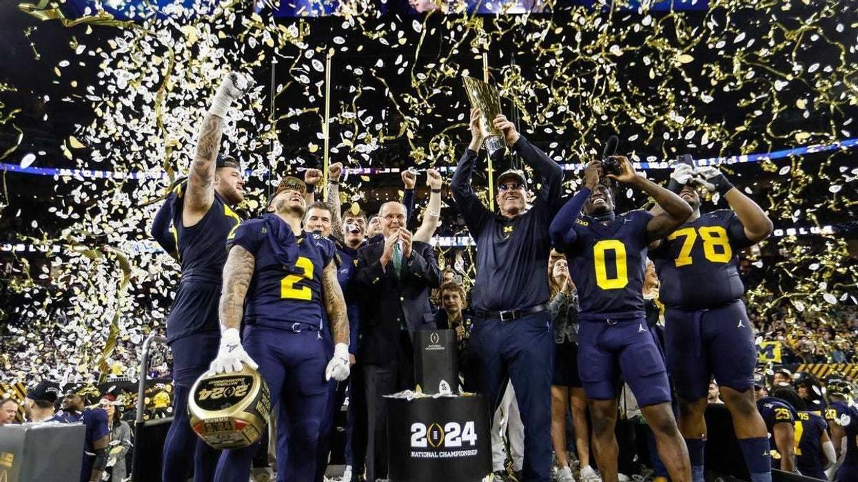 Michigan head coach Jim Harbaugh lifts up the trophy as players and coaches celebrate on stage after the 34-13 win over Washington to take the national championship game at NRG Stadium in Houston on Monday, Jan. 8, 2024.