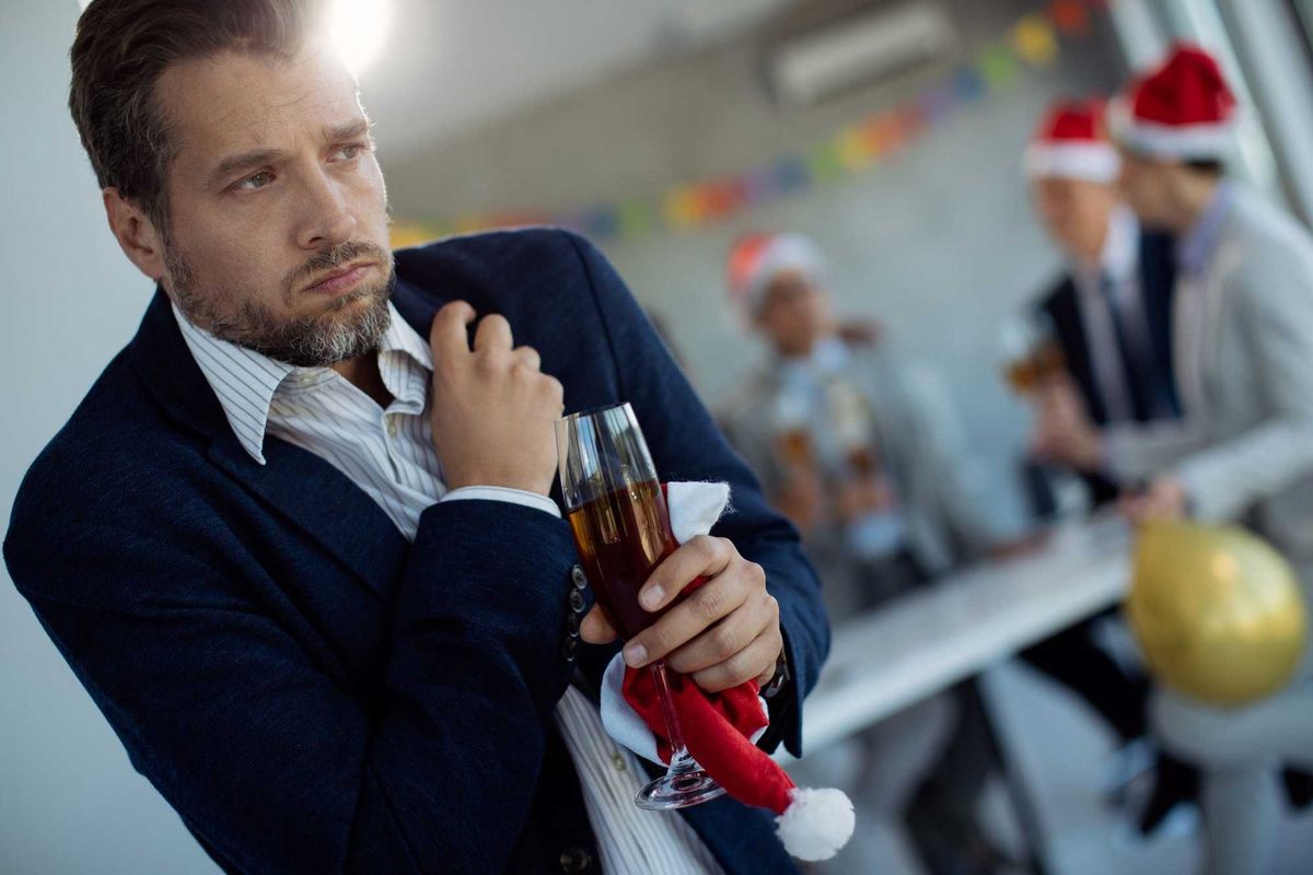 Mid adult businessman holding his chest in pain while being at Christmas party in the office.